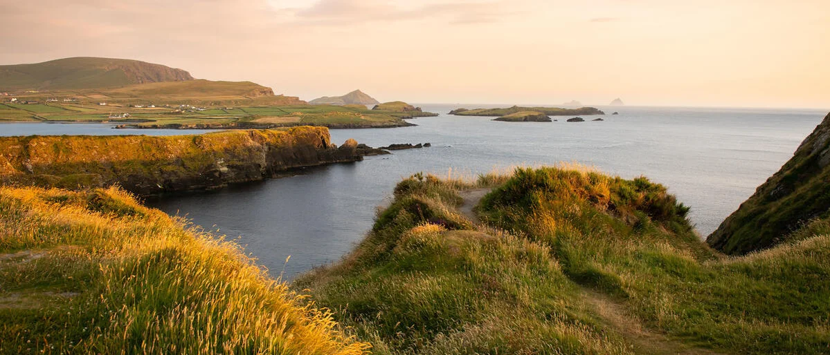 A grassy hill with a body of water and land in the background