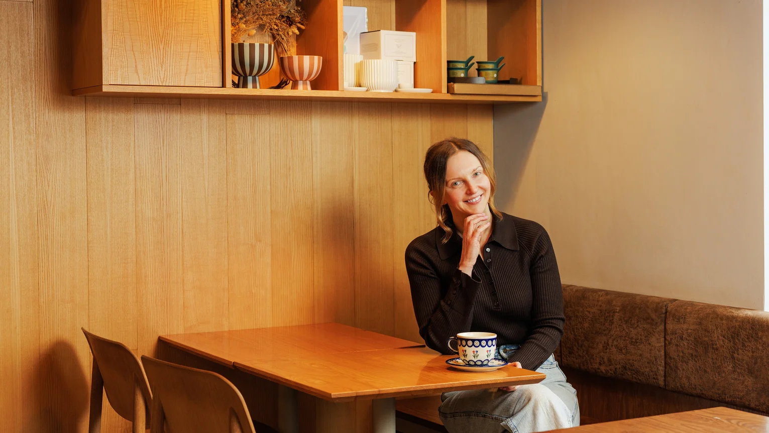 A woman sitting at a table with a cup of coffee