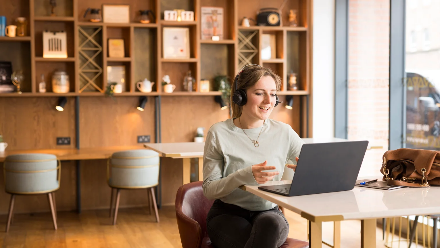 A woman wearing headphones and sitting at a table with a laptop.