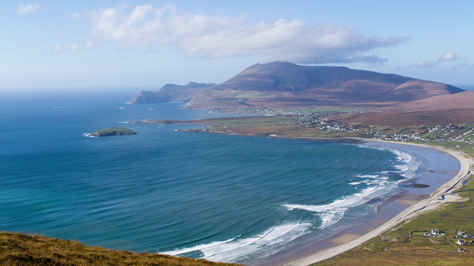 A beach with a road and mountains in the background