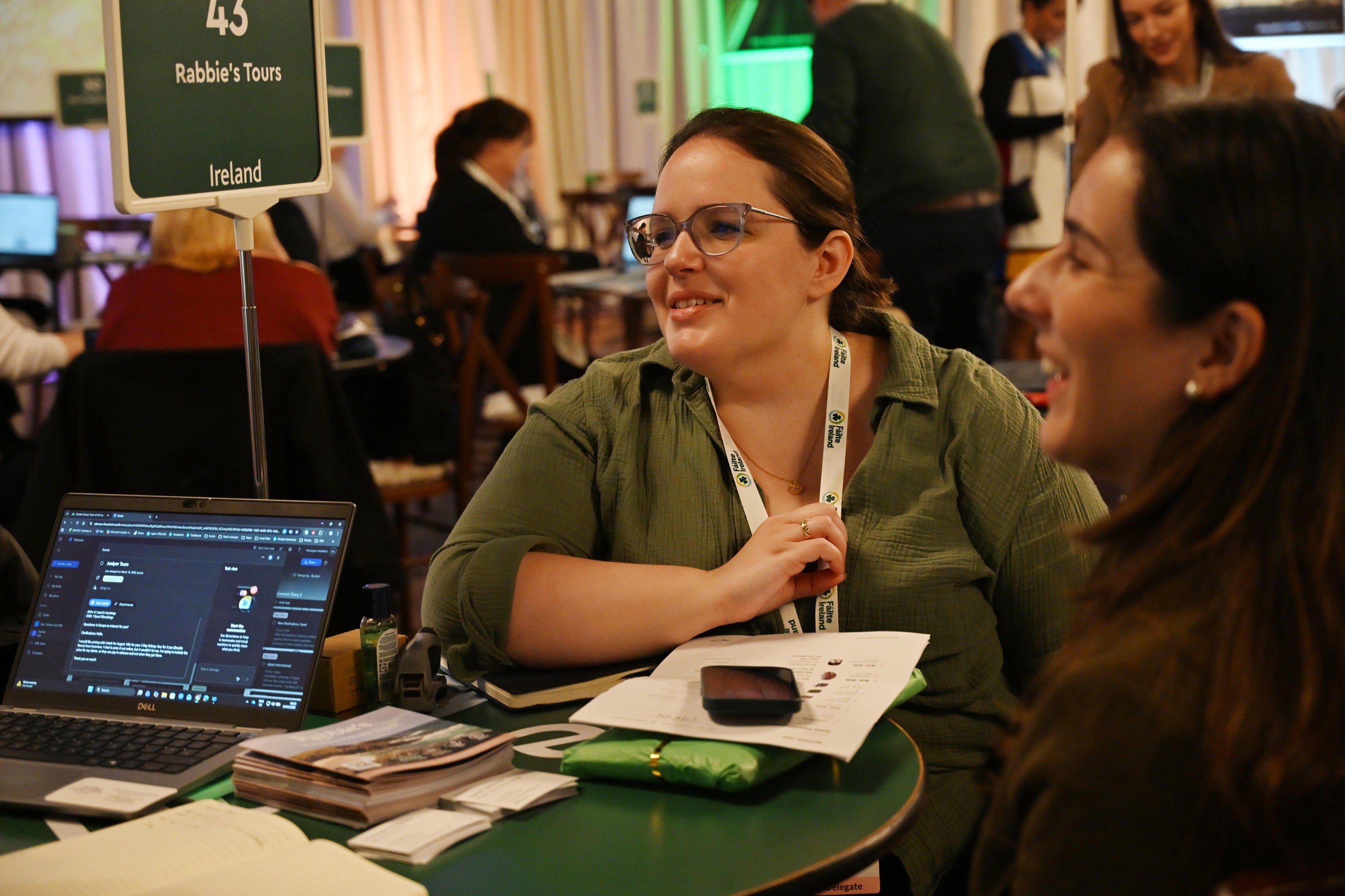 A woman sitting at a table with a laptop and a phone
