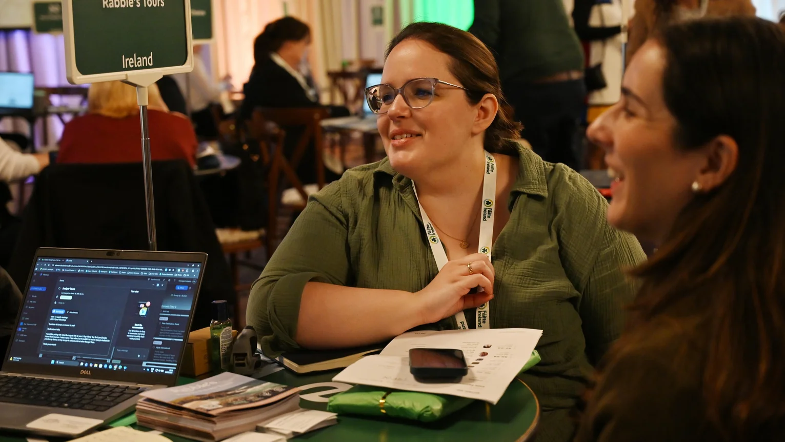 A woman sitting at a table with a laptop and a phone
