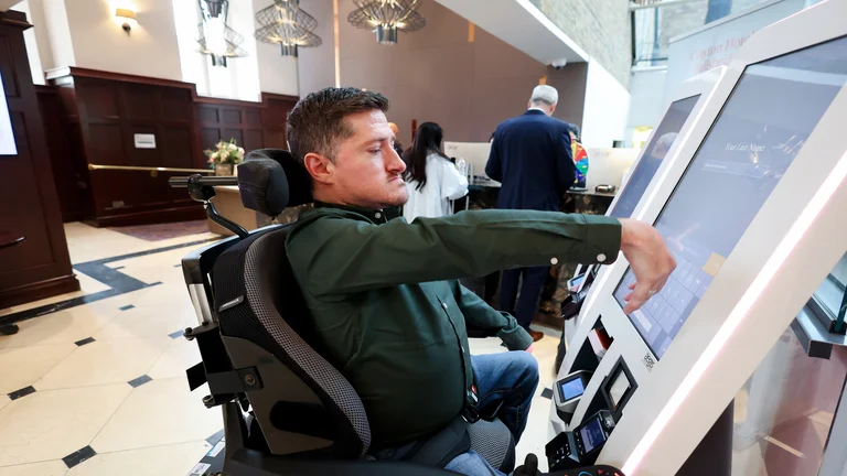 A man in a wheelchair using a computer in a hotel